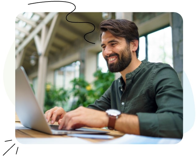 A man sitting at a desk, working on a laptop.
