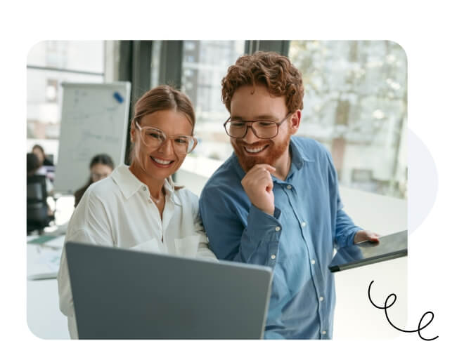 A happy man and woman with glasses smiling at the same laptop.
