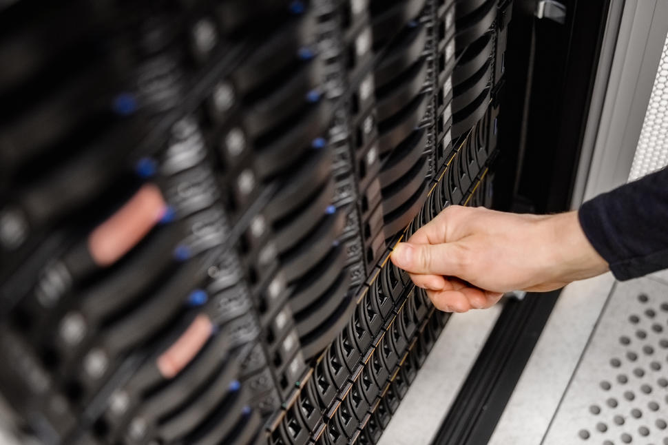 Cropped hand of male IT engineer installing server drive in SAN at datacenter