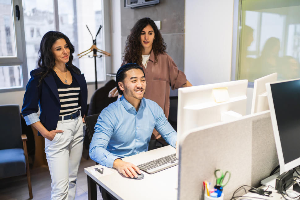 Business team collaborating on a computer in a bright, modern coworking space, fostering creativity and innovation in their project. One is chinese