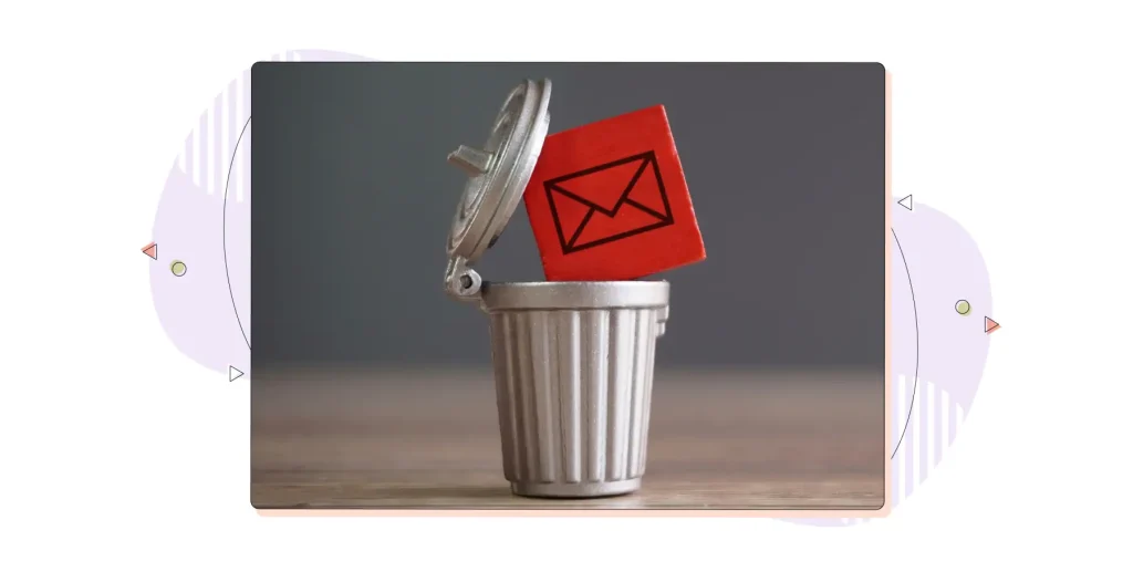 Closeup image of a wooden cube with mail icon inside a trash can