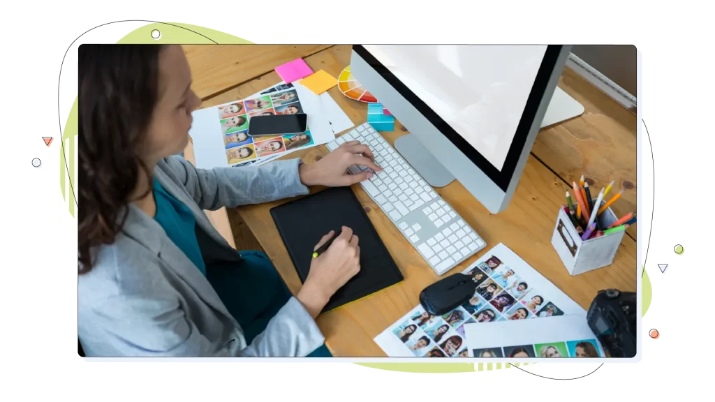 Female graphic designer using graphics tablet at desk.