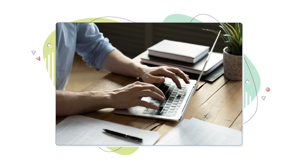 Person typing on their laptop on a wooden desk.