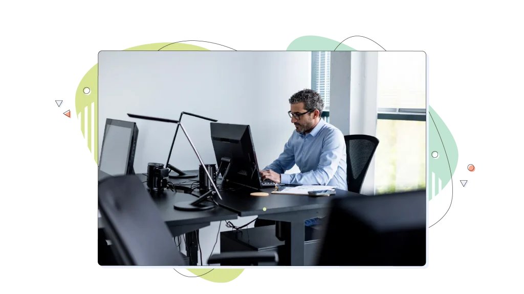 Man working in his computer in his office with other computers all around him.