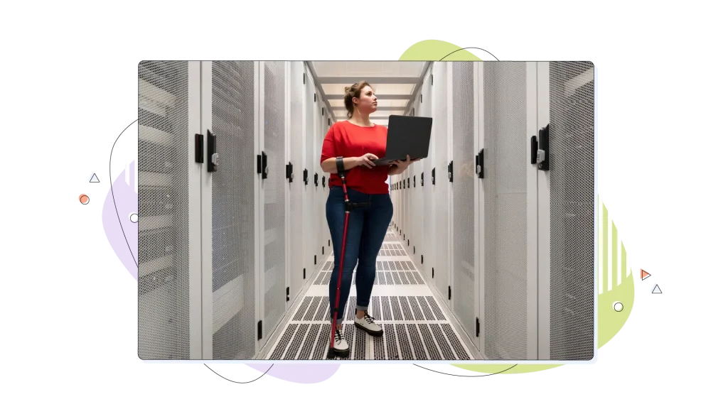 Woman working in her laptop inside a server room, inspecting the systems.