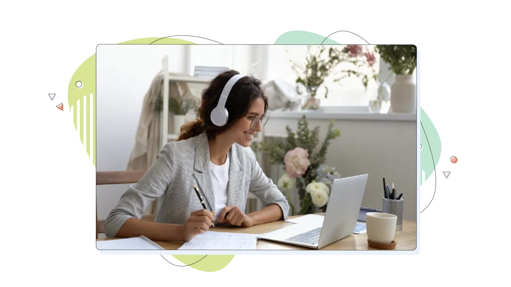 Woman working on her laptop while writing notes and listening to music.