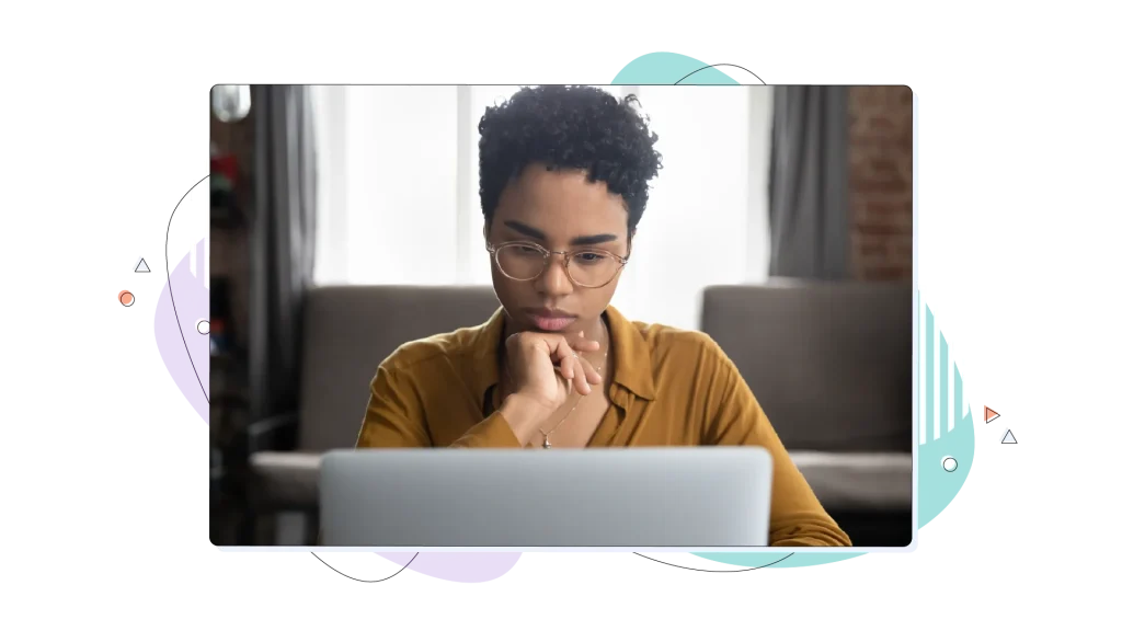 Woman with glasses working on her laptop computer, holding her hand in her face.