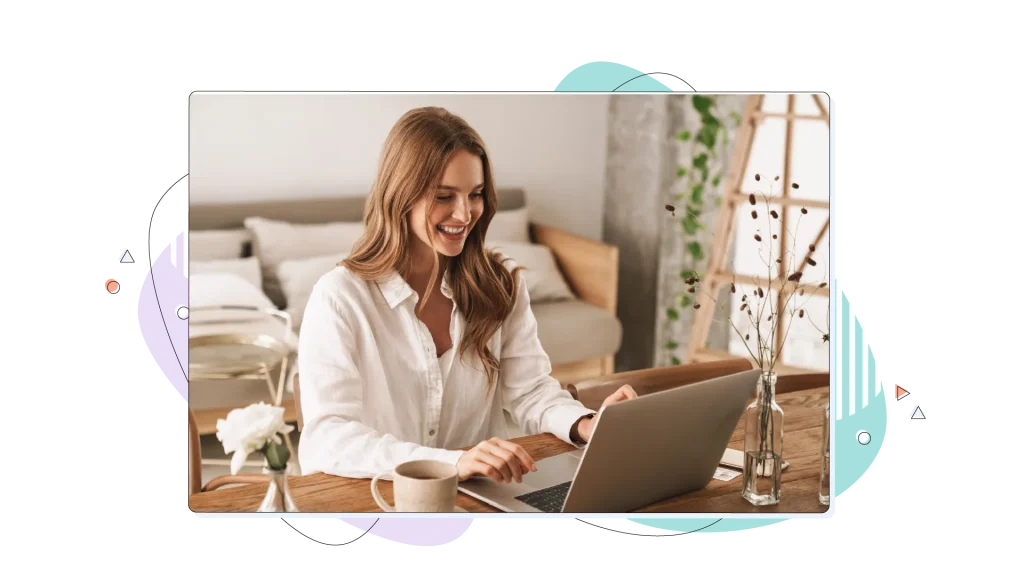Woman typing on her laptop while smiling in her well lit office.