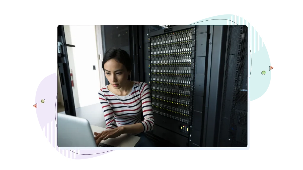 Woman typing on her laptop in a server room.