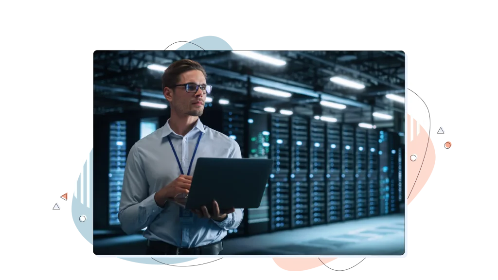 Person standing in a data centre and holding a laptop computer.