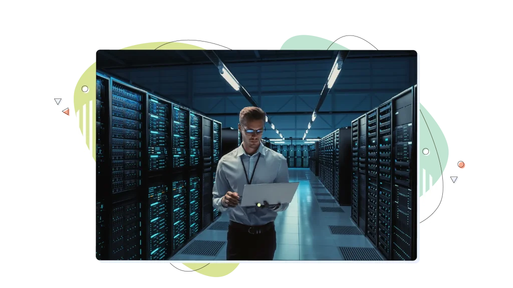 Person standing in a data centre and holding a laptop computer.