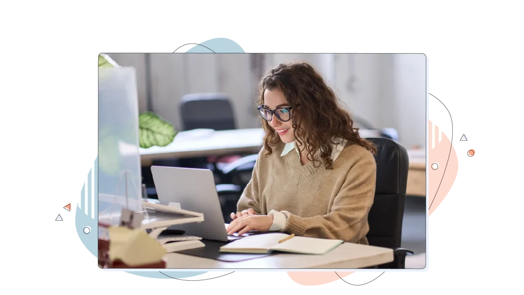 Woman working on her laptop in an office, smiling.
