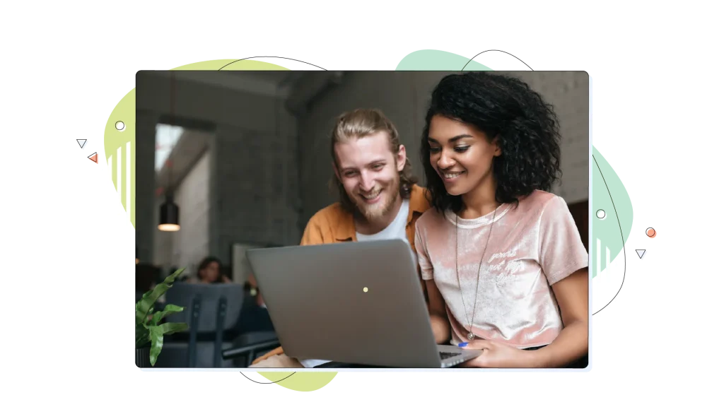 Co-workers working on their laptop, smiling. 