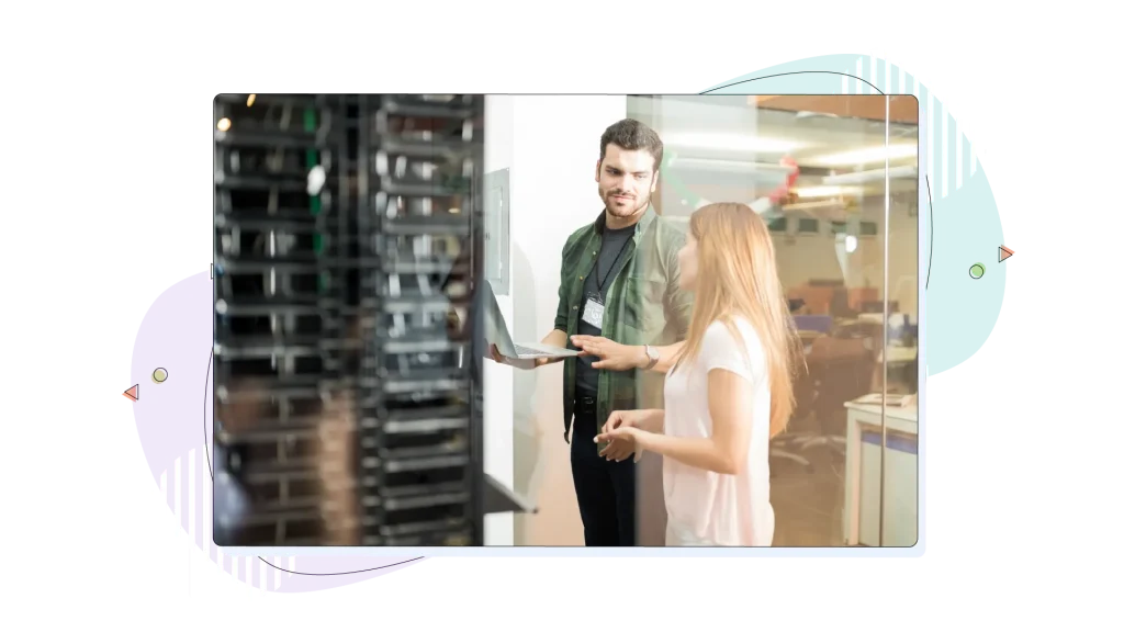 Two data centre employees working in a server room, chatting.