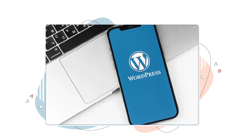 WordPress logo on a smartphone on a desk on top of a laptop.