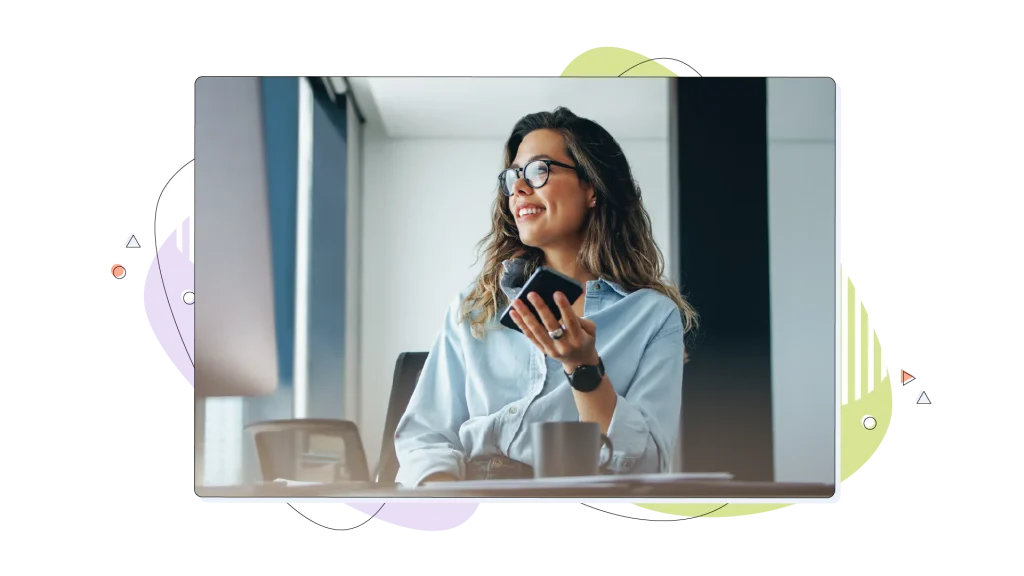 Woman talking to her phone while working on her computer.