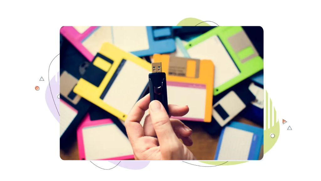 Close‑up of a hand holding a USB stick in front of multicolored disks, illustrating the data security definition in practice by protecting stored and portable digital information.