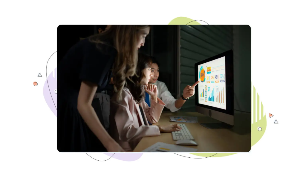 Three colleagues crowd around a computer screen discussing domain appraisal factors.