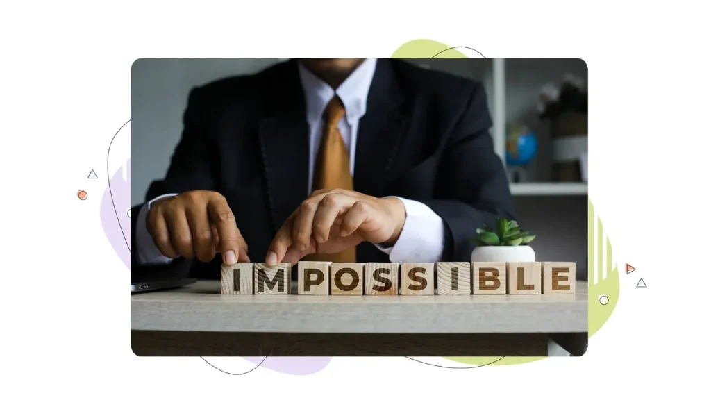 Entrepreneur takes two wooden block letters IM and separates them from the word IMPOSSIBLE on the table.
