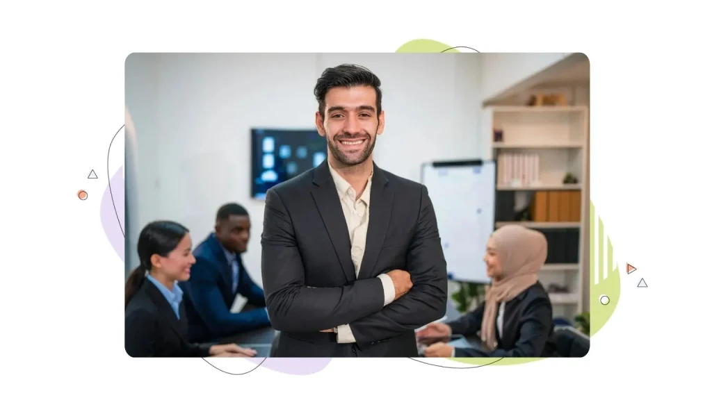 Entrepreneur smiles, while his team is talking in the background.