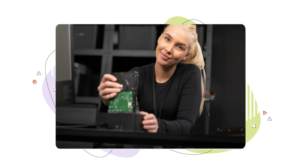 Smiling female technician installing a hard drive into a docking station, representing hands-on server setup and managed vs unmanaged VPS hosting.