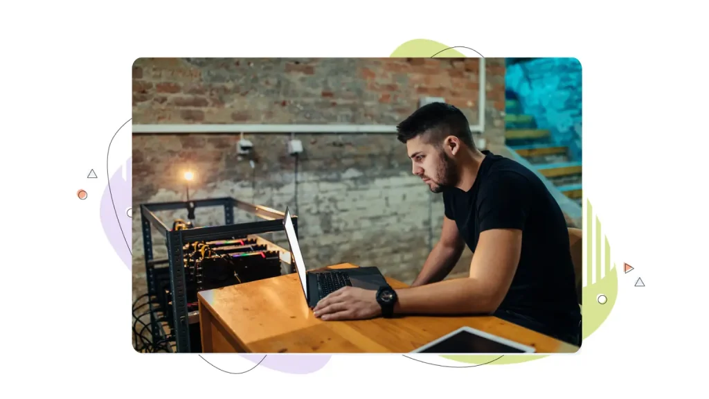 Man working on a laptop next to a sever