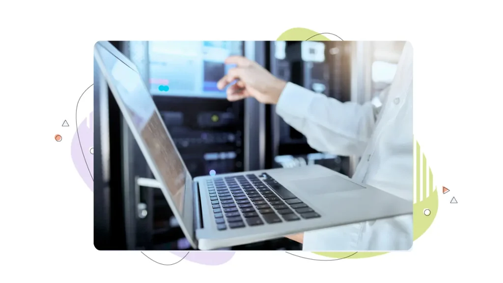 Person holding a laptop in a server room