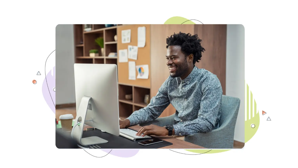 Smiling man working at a desktop computer to manage wordpress vps hosting.